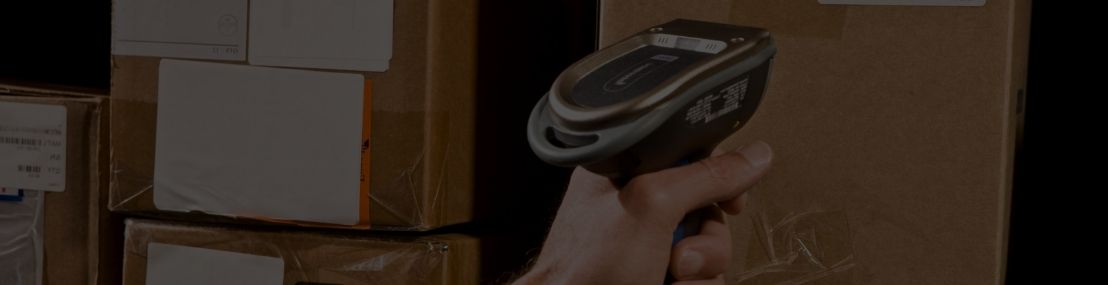 Warehouse worker pointing a barcode scanner at a barcode on a box